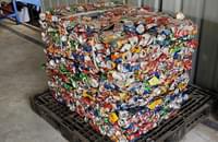 Tin cans are compressed using a bailing machine and salvaged to be recycled by registered recyclers.